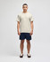 A beige short sleeve t-shirt displayed on a male model, paired with navy shorts. The shirt features a logo on the sleeve.