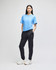 A female model wearing a blue t-shirt and black fleece joggers, featuring a logo on the joggers.