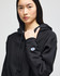 A black cropped hoodie with a hood, featuring a logo on the sleeve and a relaxed fit.