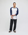 A man wearing a white and navy raglan baseball t-shirt paired with dark pants. The shirt has a logo.