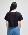 A black cropped short sleeve T-shirt with a plain back, paired with blue denim jeans.