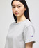 A light grey cropped short sleeve jersey t-shirt with a logo on the sleeve.