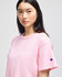 A pink cropped short sleeve t-shirt with a logo on the sleeve, featuring a relaxed fit and soft fabric.