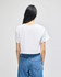 A white cropped short sleeve t-shirt displayed from the back, paired with blue jeans. The shirt features a logo.