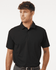 A black polo shirt with short sleeves, featuring a collar and a logo, modelled by a man.
