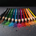 A set of 12 colouring pencils in various vibrant colours, arranged beside shavings of different hues.