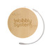 A round bamboo coaster with a textured surface and a silver loop attached, featuring the words "Wobbly System".
