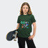 A green youth T-shirt featuring a graphic design with trees and geometric shapes, held by a child with a skateboard.