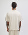 A boxy unisex t-shirt in a light beige colour, featuring short sleeves and a plain design, with a logo on the back.