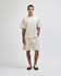 A model wears a light beige heavyweight cotton unisex boxy t-shirt and matching shorts, featuring a logo.