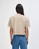 A heavyweight cotton women's crop t-shirt in beige, featuring a boxy fit and branding on the back.