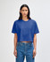 A blue, heavyweight cotton women's crop boxy T-shirt displayed on a model, featuring a logo.