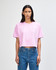 A pink heavyweight cotton women's garment dyed crop boxy t-shirt, paired with blue jeans, featuring a logo.