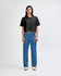 A black crop boxy T-shirt paired with blue straight-leg jeans, modelled by a standing woman. The outfit features a logo.