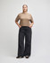 A mid-length boxy top in beige, worn with black wide-legged jeans. The top has a brand logo on it.