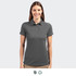 A women's polo shirt in dark grey, featuring a collar and logo. The model is smiling and facing forward.
