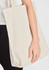 A cream canvas tote bag held by a person, featuring sturdy handles and a simple design.