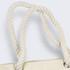A close-up of the twisted, cream-coloured rope handles of a tote bag featuring silver eyelets.