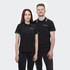A black polo shirt featuring contrasting green and white collar details, worn by two models. The shirt has a logo.