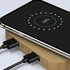 A bamboo wireless charging hub with a smartphone displaying charging status. The hub has two connected cables.
