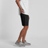 Black sports shorts featuring an elastic waistband and a logo, worn with a plain white t-shirt and grey sneakers.