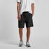 Black sports shorts with an elastic waistband, modelled by a person wearing a white t-shirt and grey sneakers.