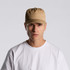 A beige soft cap worn by a model, featuring a simple design and a prominent logo.