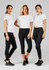 Three women in white t-shirts and black leggings, standing together against a grey background. The leggings have a logo.