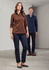 A brown long sleeve button-up shirt worn by a woman, paired with dark trousers; a man in a navy shirt stands behind.