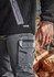 A close-up of men's grey work pants featuring multiple pockets and a zipped side pocket, paired with a black fleece top.