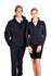 A man and woman wear matching black jackets with white accents, featuring a branding logo. The woman pairs hers with a skirt.