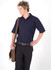A man in a navy blue polo shirt poses with a brown messenger bag, wearing black trousers and a belt.