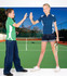A green and blue polo shirt is worn by two children on a tennis court, with tennis racquets in hand.