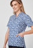 A short-sleeve tunic in blue with a stardust print, featuring a collar and side pockets, alongside a model.