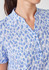 A blue and white tunic featuring a stardust print, with a collared neckline and button details.