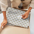 Tissue paper in white with a patterned design, inside a cardboard box, being handled by a person.
