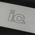 A stainless steel blade with an engraved logo set against a textured black background.