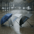 Three umbrellas in blue, white, and black, each featuring a logo, set against a rainy street backdrop.