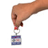 A hand holding a square acrylic keychain featuring a logo and text, predominantly red, blue, and silver.