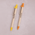 Two wooden pens in yellow and orange with a brand logo on each.