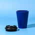 A blue reusable coffee mug with a black lid, made from recycled materials.