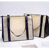 Two large zipped shopping bags in beige and black, featuring handles and a branding logo.