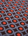 Lambretta Mens Geometric Target Retro Mod Ska Casual T-Shirt, close-up of the fabric showcasing a repeating pattern of orange circles surrounded by blue rings on a dark background.