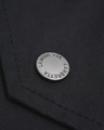 Lambretta Mens Shower Resistant Hooded Classic Badge Fishtail Parka, close-up of the metal badge on the black waterproof fabric.