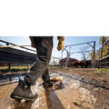 Muck Boots MUCK Chore Classic Chelsea Mens Stable Farm Wellington Wellie Ankle Boots, black waterproof work boots with slip-resistant soles worn by a person walking through muddy farmyard.