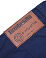Lambretta Mens Chino Casual Classic Shorts, close-up of the leather brand label on navy blue chino shorts with stitching detail.