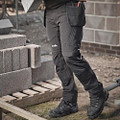Scruffs Tech Holster Mens Multi Pocket Workwear Trousers, close-up of black multi-pocket work trousers with zipper pockets and tool holster, worn by a construction worker on site.
