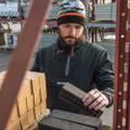 Scruffs Over-Head Jacket Mens Lightweight Work Jacket Coat, man working with bricks at construction site, wearing black waterproof jacket with hood and beanie hat