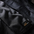 Scruffs Pro Flex Mens Holster Multi-Pocket Cordura Stretch Workwear Trousers, close-up of durable black fabric with a black and gold label.