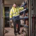 Scruffs High Visibility Mens Hi-Viz Work Pull Over Hoodie, man in high visibility yellow hoodie with reflective stripes in a warehouse setting.